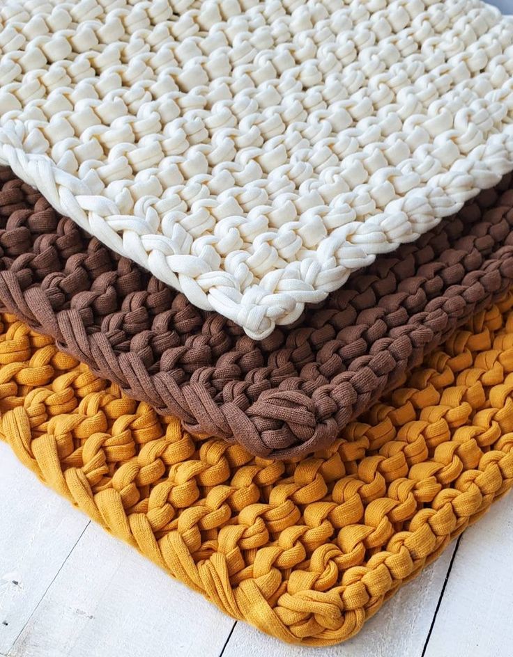 three different colored knitted rugs stacked on top of each other in the same pattern