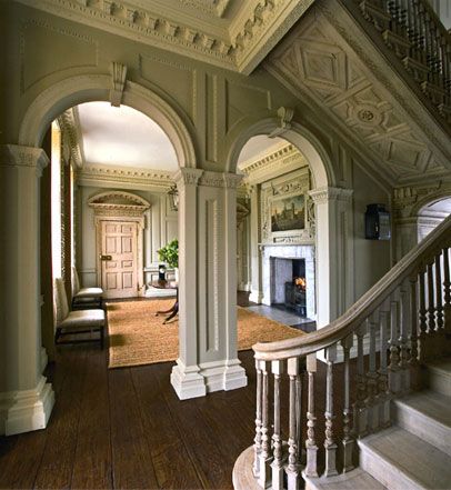 an ornate entry way with stairs and arches leading up to the second floor, along with a fireplace