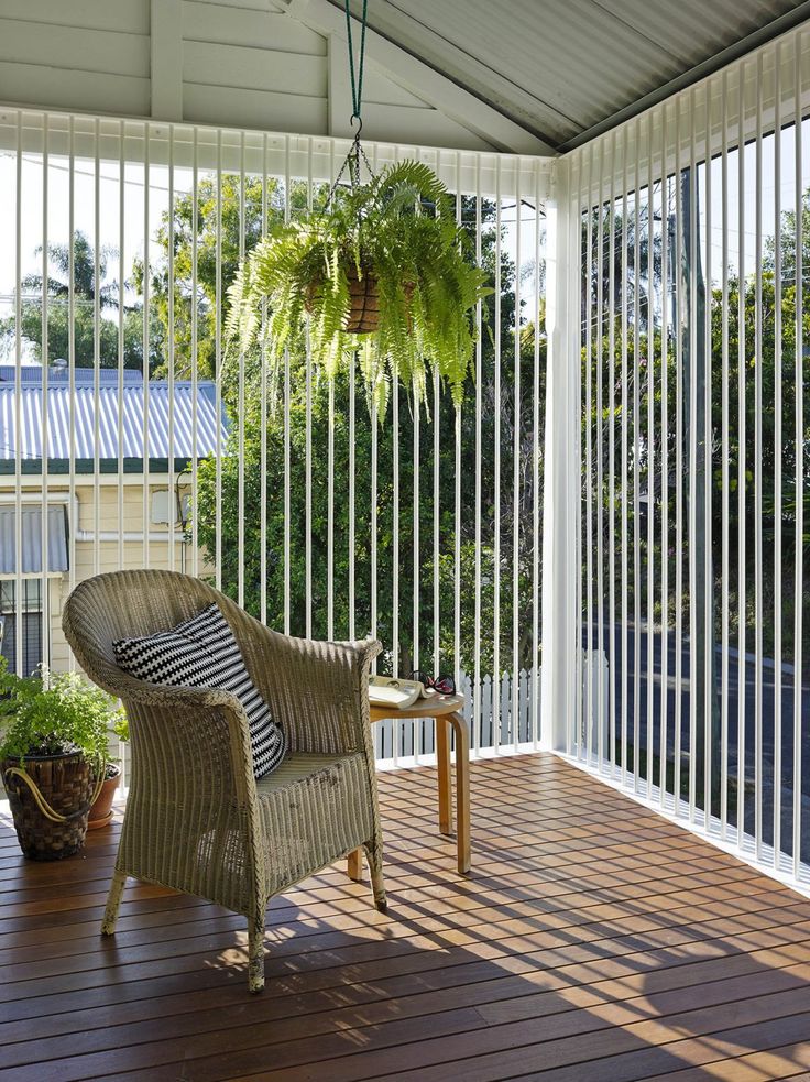 a wicker chair sitting on top of a wooden deck next to a potted plant