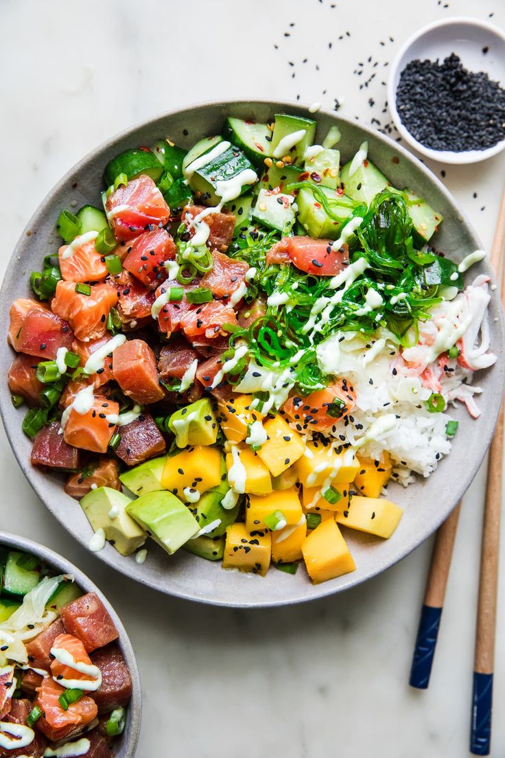 two bowls filled with food next to chopsticks