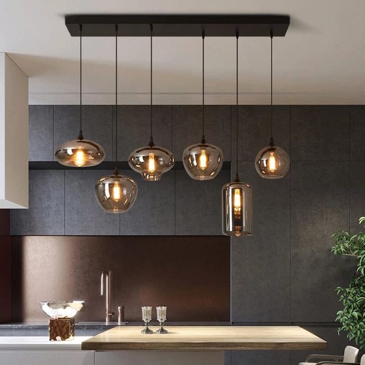 a modern kitchen with an island and hanging lights above the countertop, surrounded by chairs