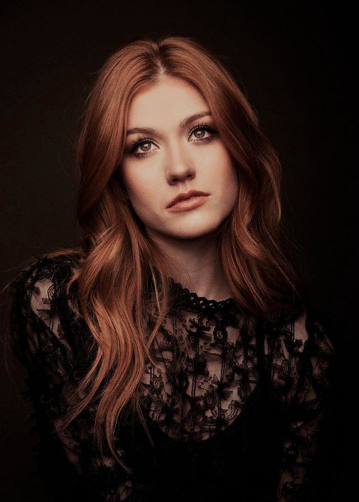 a woman with long red hair is posing for a photo in a black lace top