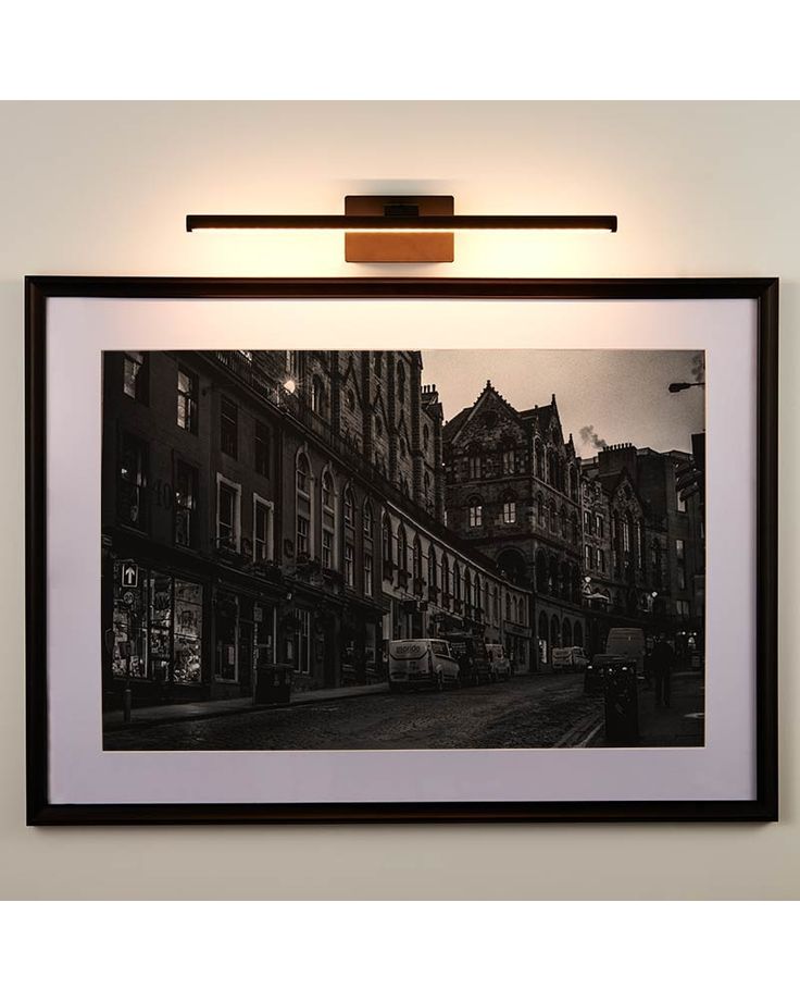 a black and white photo hanging on the wall next to a light that is above it