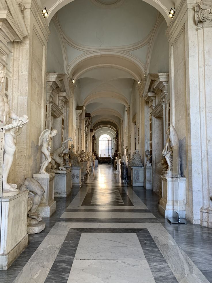 the hallway is lined with marble statues and sculptures on either side of the entrance way