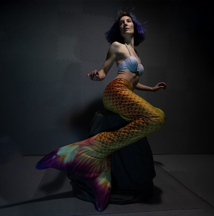 a woman with blue hair is posing in a mermaid costume