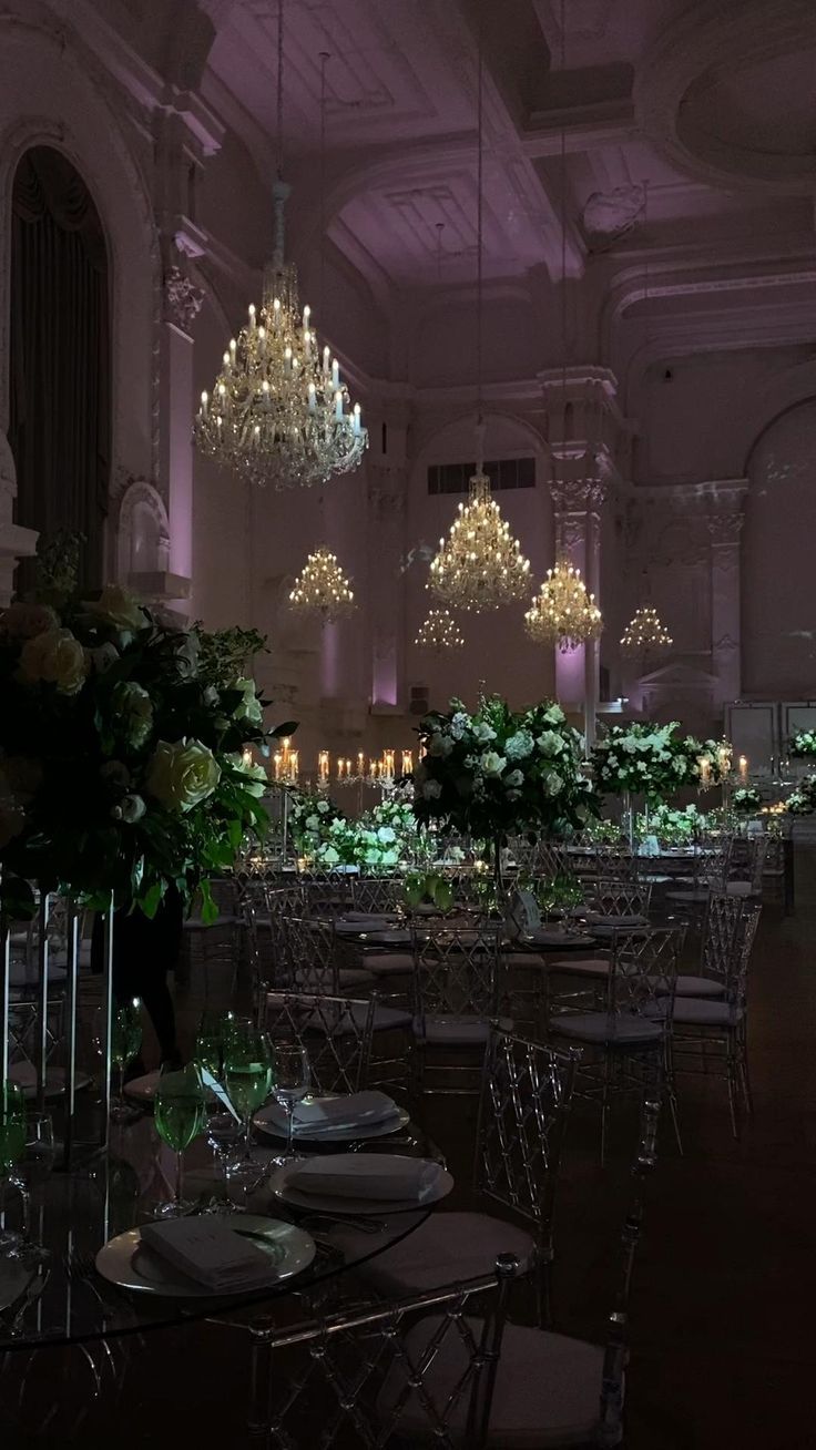 the tables are set up for an event with chandeliers hanging from the ceiling