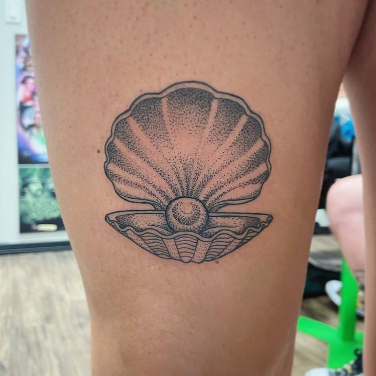 a woman's thigh with a tattoo of a shell on it