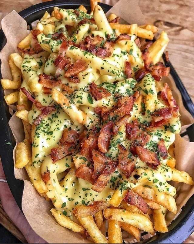 a plate filled with french fries covered in cheese and bacon