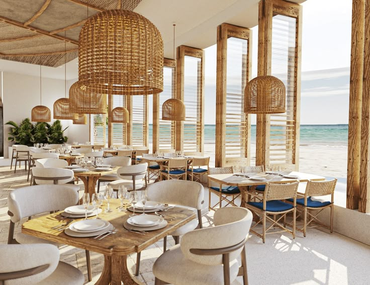 a restaurant with tables and chairs overlooking the ocean in front of large windows that look out onto the beach