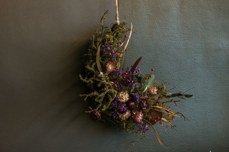 a wreath hanging on the wall with flowers and branches attached to it's sides