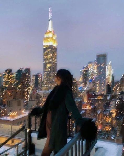 a woman standing on top of a building looking at the city