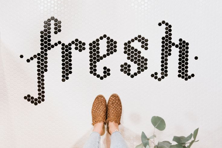 a person standing in front of a white wall with the word fresh written on it