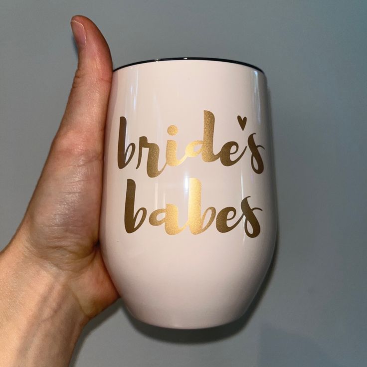 a hand holding a wine glass with the words bride's babes written on it