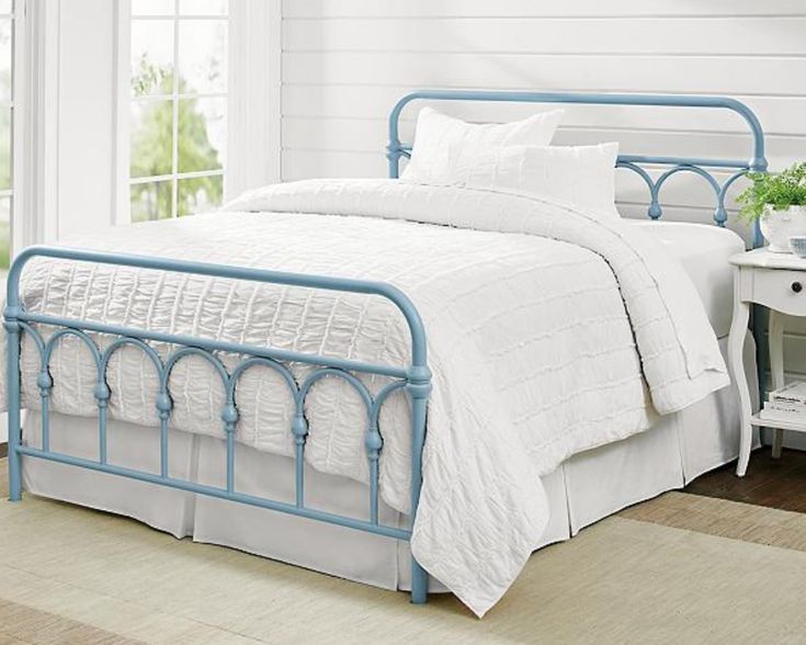 a white bed with blue metal frame and pillows