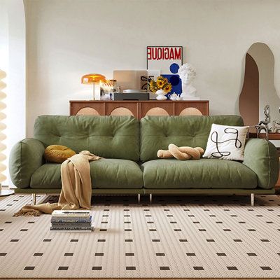 a green couch sitting on top of a rug in a living room