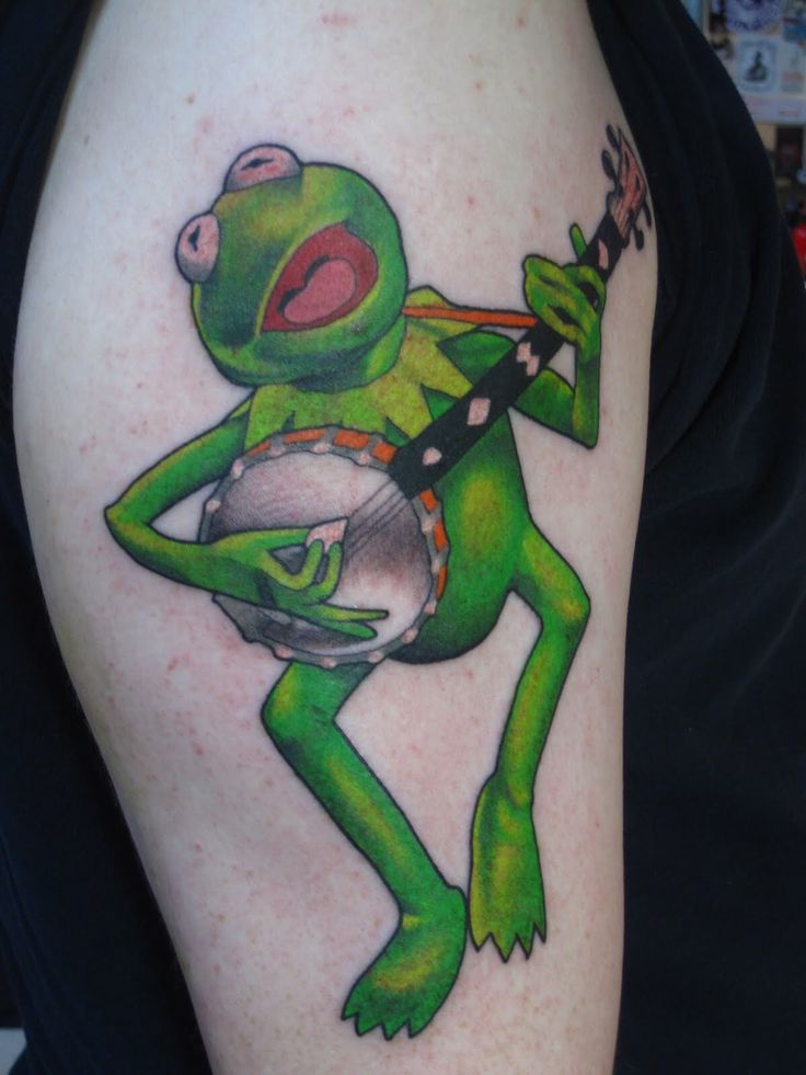 a person with a green frog tattoo on their arm holding a silver object in his right hand