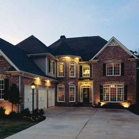 a large brick house with lights on the front door and windows in the side yard