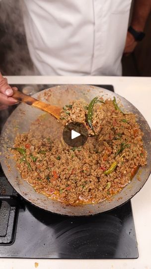 a person cooking food on top of a stove with a wooden spatula in it