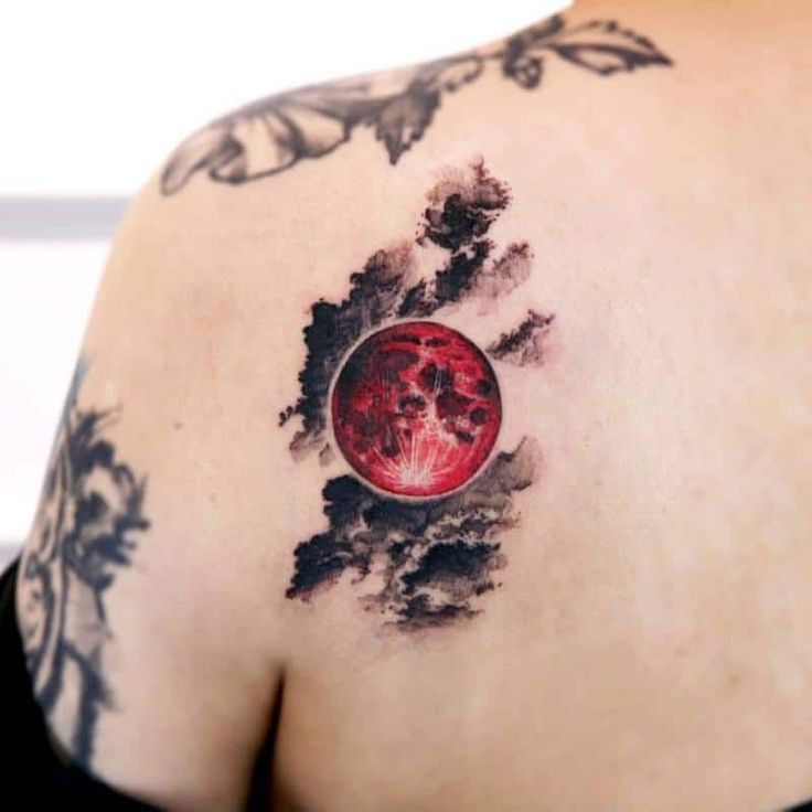 a woman's back with a red and black tattoo on her upper half sleeve