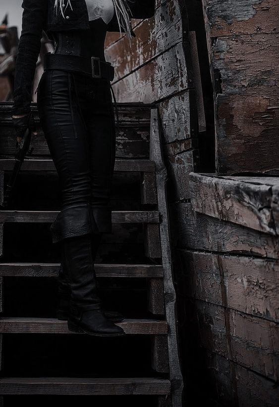 a woman dressed in black and white is standing on stairs with an umbrella over her head