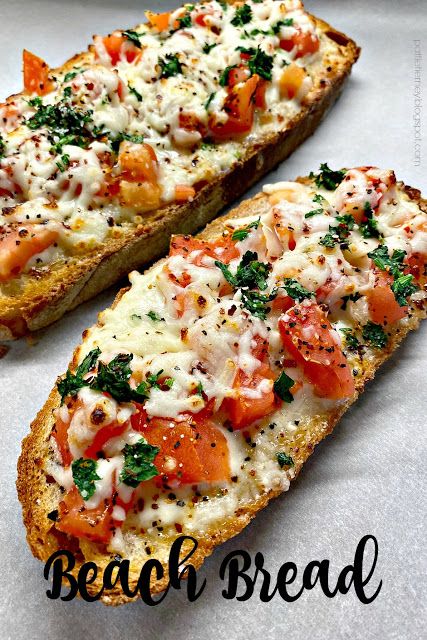 two pieces of bread with tomatoes and cheese on them, sitting on a white surface