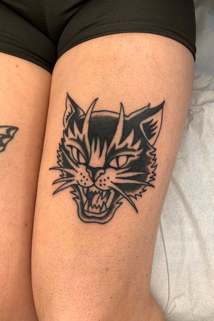 two black and white tattoos on the legs of people with cats'heads in them