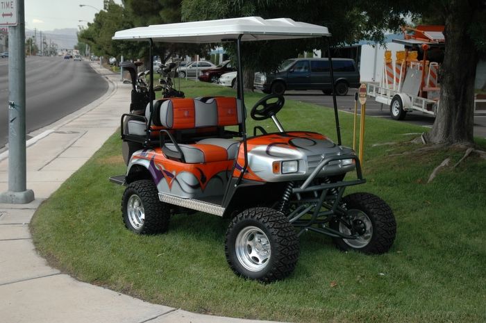 an orange and gray golf cart parked on the grass