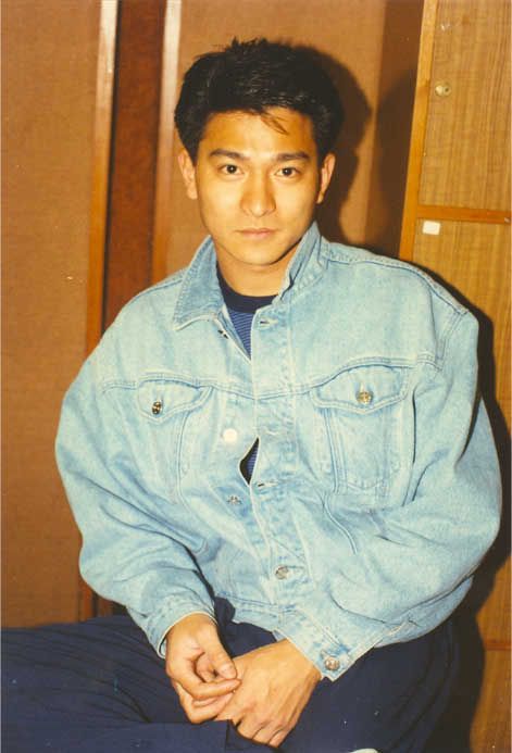 a young man sitting on the floor wearing a jean jacket