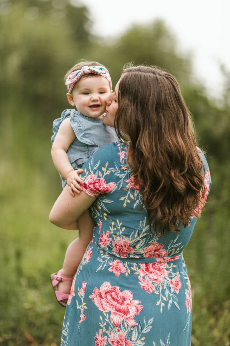 a woman holding a baby in her arms and kissing it's face with the other hand