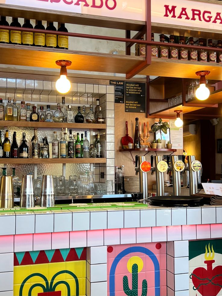 the interior of a mexican restaurant with many bottles on the bar and lights above it