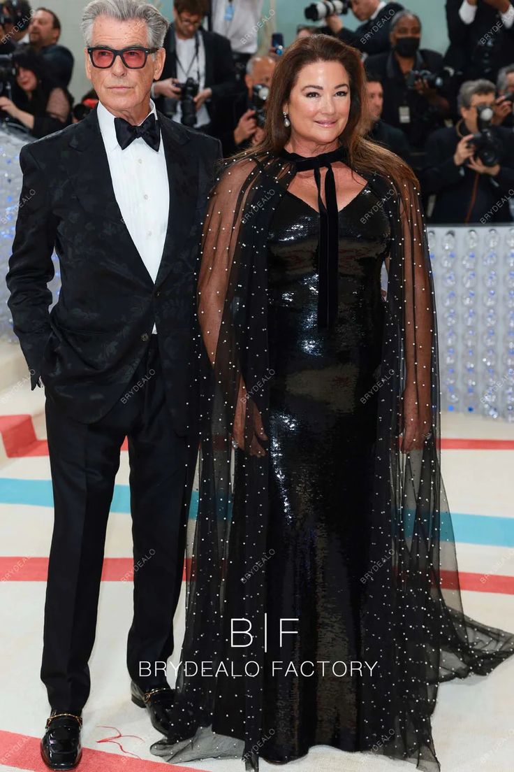 an older man and woman in formal wear standing next to each other on the red carpet