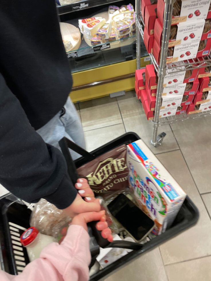 a person pushing a cart full of food in a store with another person standing next to it