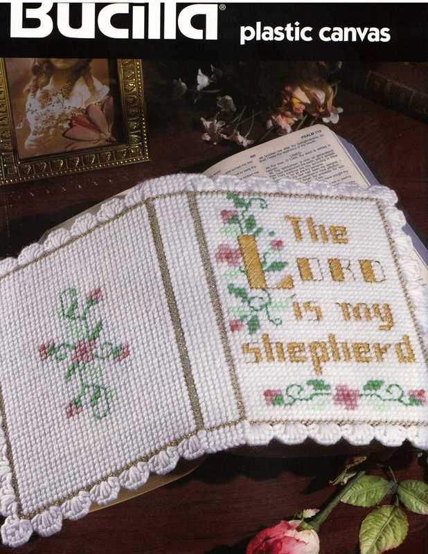 the cross stitch book is next to a rose