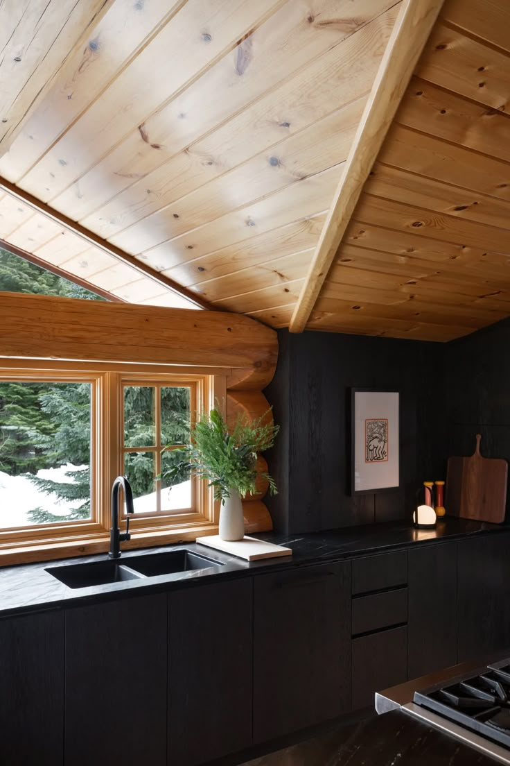 a kitchen with black counter tops and wooden ceiling