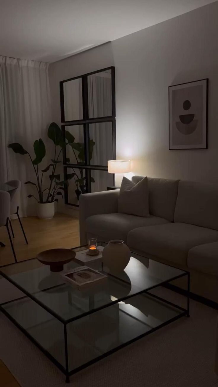 a living room with a couch, coffee table and lamp in it's center