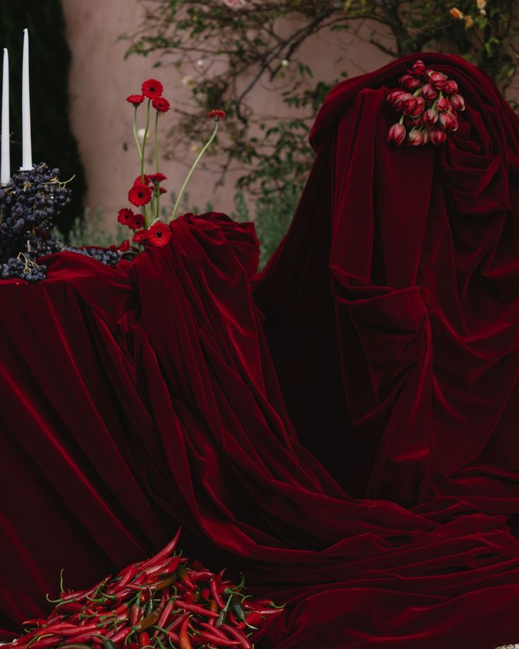 two red cloths with flowers and candles in the background, one is draped over