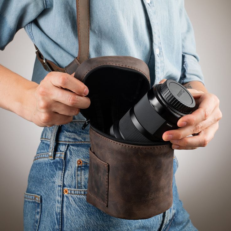 a person holding a camera in their back pocket with the lens attached to his shoulder