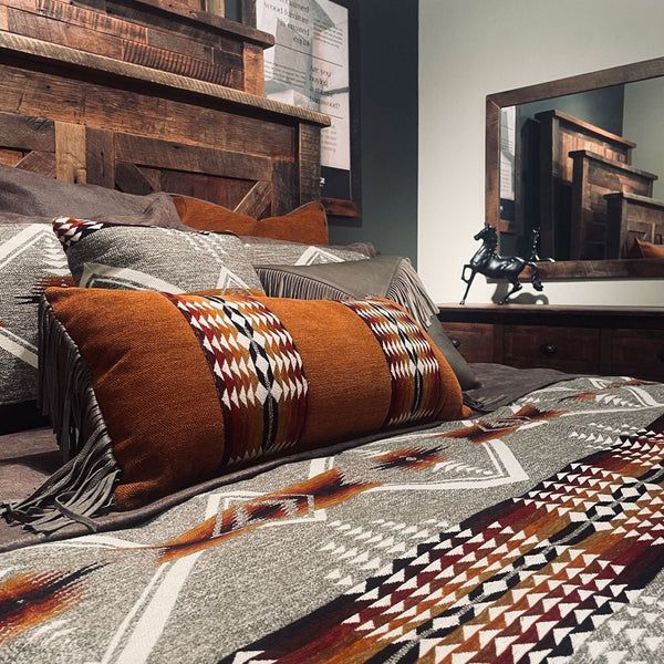 a bed with pillows and blankets on top of it in front of a large mirror