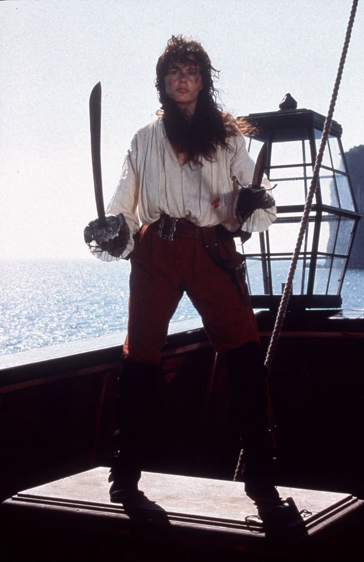 a man dressed in pirate garb standing on the deck of a ship with his arms crossed