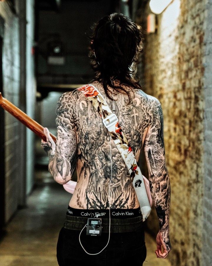 a man with tattoos holding a baseball bat