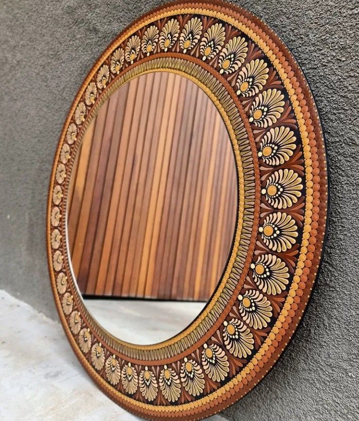 a wooden mirror hanging on the side of a wall