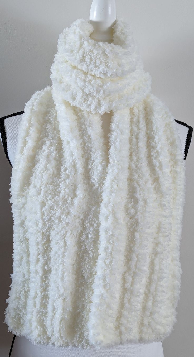 a white knitted shawl hanging on a mannequin