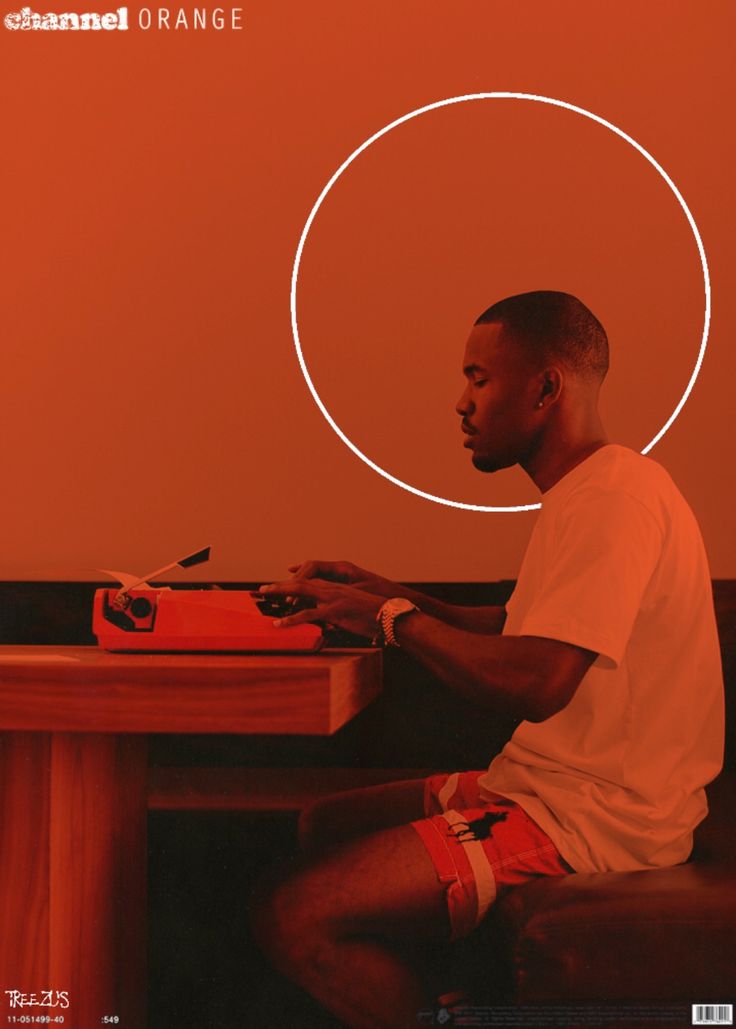 a man sitting at a table with a laptop in front of an orange circle on the wall