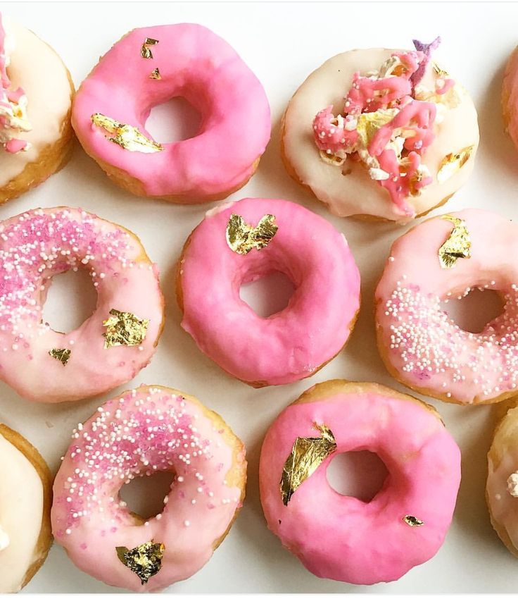 a bunch of doughnuts with pink frosting and sprinkles