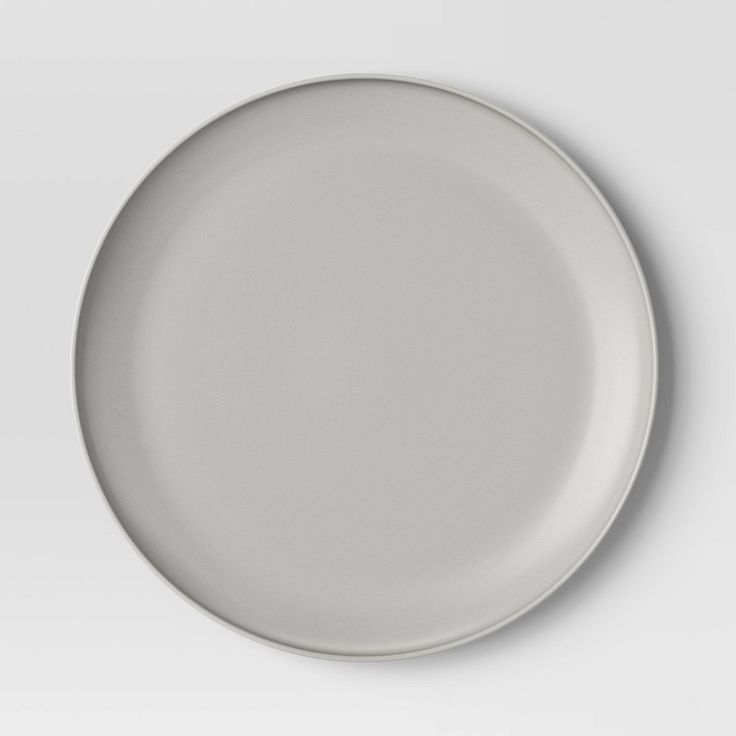 an empty white plate is shown on a plain surface with no one around it,