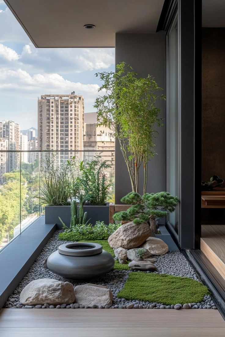 an indoor garden with rocks and plants on the ground, in front of a large window