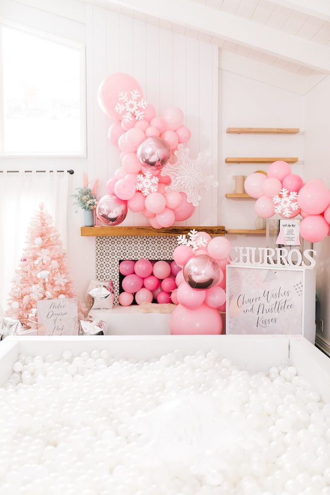 pink and silver balloons are on display in a room decorated for christmas with snowflakes