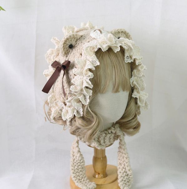 a mannequin head wearing a crocheted hat with flowers on it's side