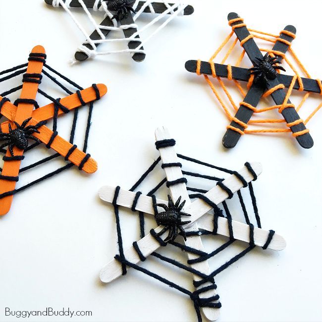 three halloween spider webs made out of black and white paper with orange and black pins