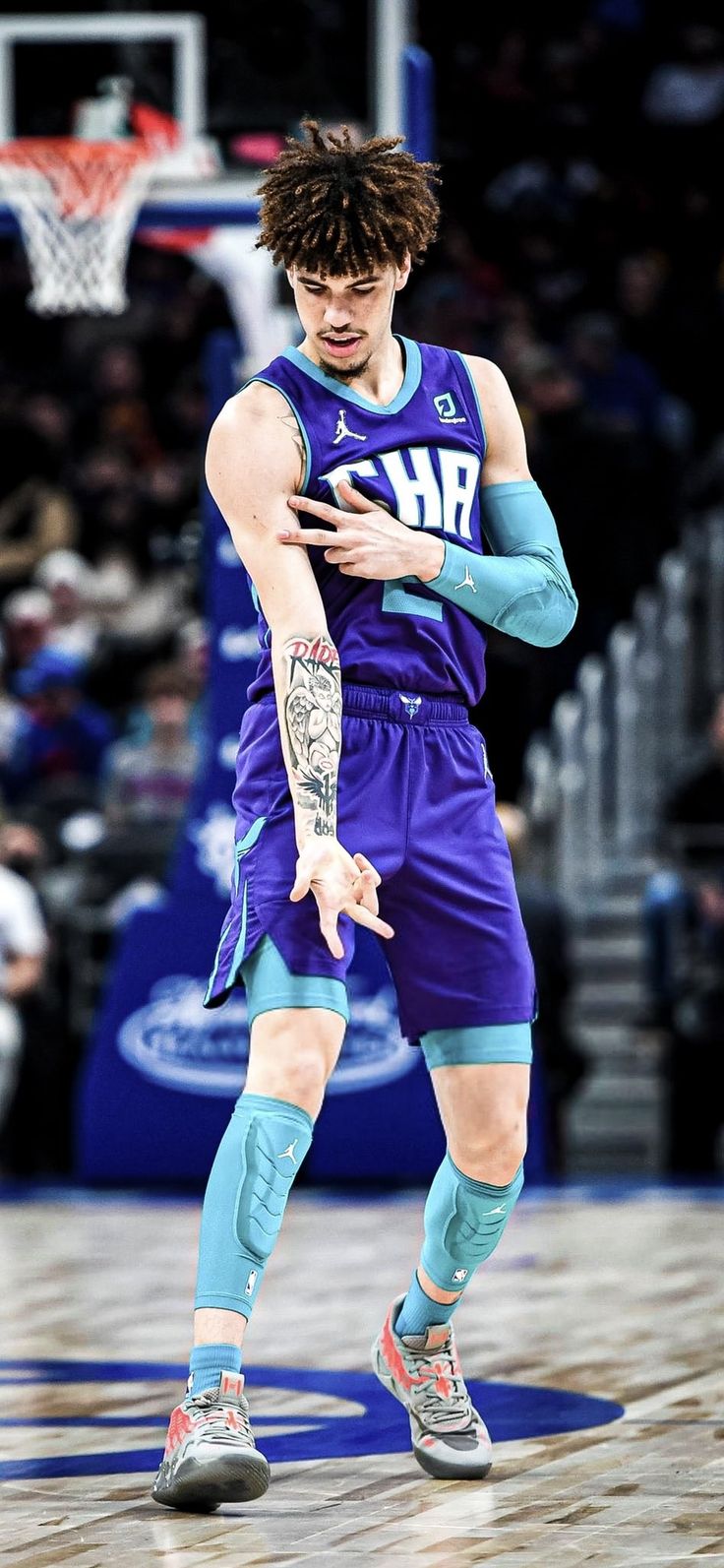 a basketball player holding his cell phone while standing on the court